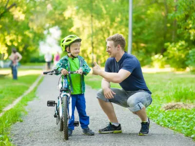 gro-up volwassene man geeft een compliment aan een jongen dat leert fietsen