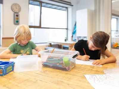 Kinderen maken kleurplaat aan tafel van kinderopvang locatie.
