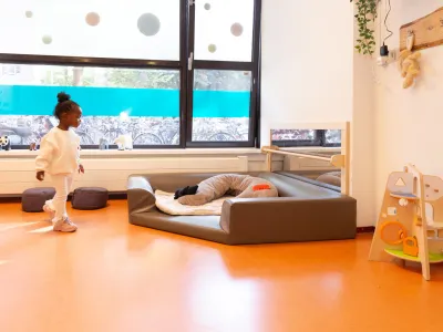 Peuter loopt in groepsruimte van kinderdagverblijf.