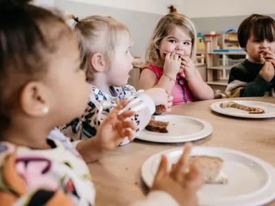 vier peuters eten broodjes aan tafel op het kinderdagverblijf