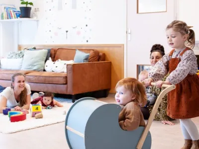 peuter duwt een baby in de wandelwagen op het kinderdagverblijf van Impuls
