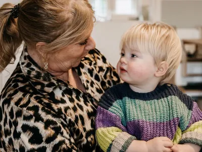 pedagogisch medewerker kijkt naar peuter op schoot