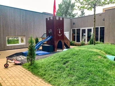 buitenspeelplaats met grasheuvel en speelkasteel op de achtergrond