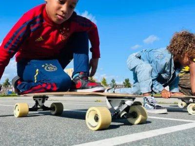 Twee kinderen op de buitenschoolse opvang spelen met een skateboard op het terrein van Kindercentrum De Bloeiboei in Almere.