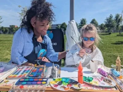 Ailyne Stein, oprichter van De Bloeiboei, schildert buiten met een kind aan tafel aan knutselprojecten.