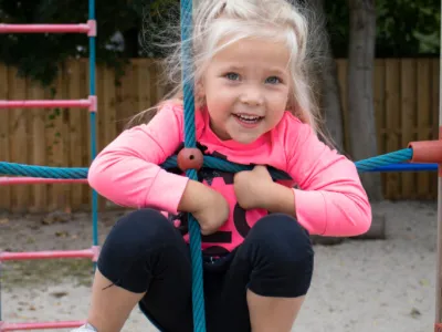 Meisje dat in de klimtouwen hangt op het speelplein