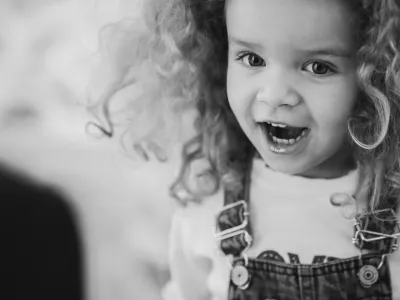 Playful black and white portrait of a happy child laughing, capturing pure innocence and joy.