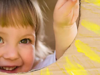 Little child looking through window of children's house made of big box