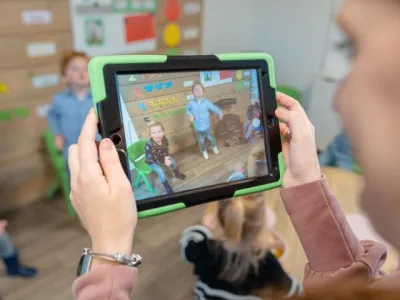 Pedagogisch medewerker gebruikt tablet om foto te maken