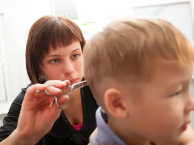 Hairdresser trimming a small boys hair