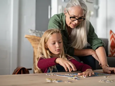 Girl doing jigsaw puzzle with grandmother