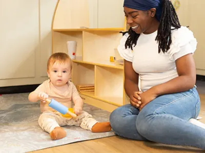 Pedagogisch professional speelt met een dreumes op het kinderdagverblijf.