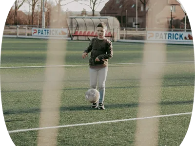 Jongen die aan het voetballen is op een voetbalveld