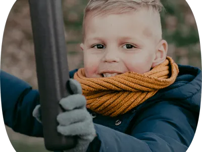 Jongetje met sjaal om die lacht en kijkt naar de camera