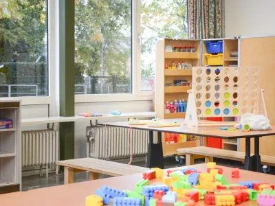De ruimte van de BSO in Wessem. Er ligt speelgoed op tafel. Buiten zijn er bomen te zien door grote ramen.