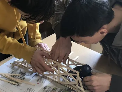 Students build a bridge of sticks together