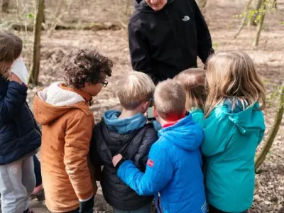pedagogisch professional geeft natuurles in het bos aan de bso-kinderen