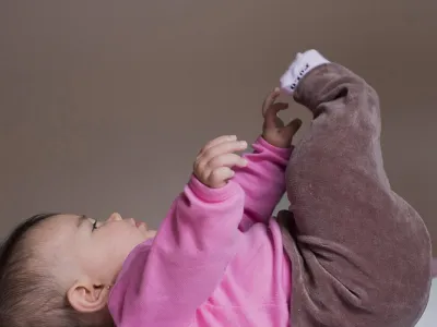 Baby op rug reikt naar benen