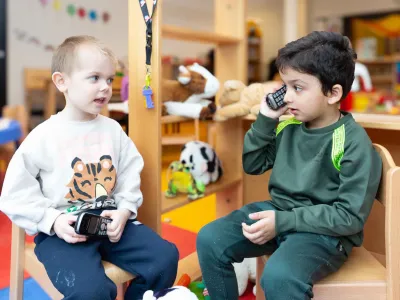 Jongens zitten op een stoel en spelen met een telefoon bij de kinderopvang.