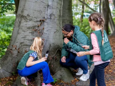Kinderen en pedagogisch professional kijken samen naar een boom in de natuur