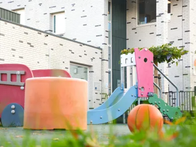 Een laag perspectief van het gebouw in Thorn. Er staan verschillende speeltoestellen in felle kleuren.