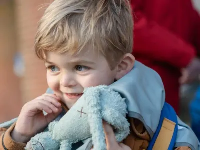 Kind lacht met knuffeltje in de hand