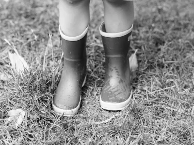 Kind met regenlaarsjes speelt buiten bij The Kids Company dagopvang in Veldhoven
