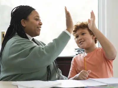 gro-up jeugdhulpverlener geeft een high five aan een jongen die schoolbegeleiding krijgt